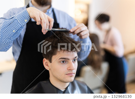 Male hairdresser giving haircut to young guy 132968130