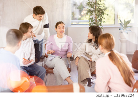 Cheerful girl student discussing learning assignment with coursemates 132968224