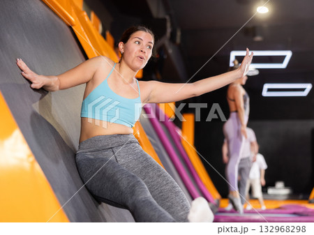 Young woman in sport clothes jumping on vertical trampoline Young woman in sport clothes jumping on vertical trampoline 132968298