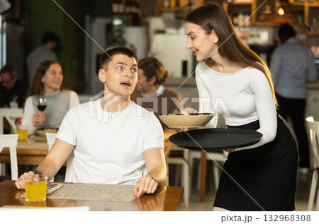 Guy makes an order in a restaurant with a female waitress Guy makes an order in a restaurant with a female waitress 132968308