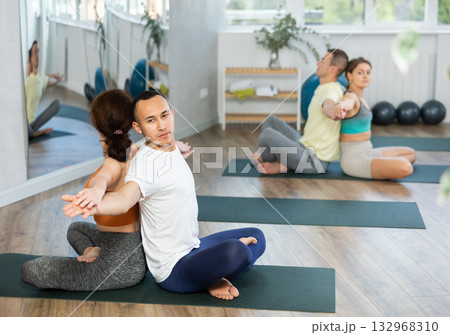 Men and women maintaining healthy lifestyle practicing partner yoga at group lesson Men and women maintaining healthy lifestyle practicing partner yoga at group lesson 132968310