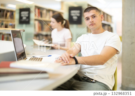Student guy reading books and working on laptop Student guy reading books and working on laptop 132968351
