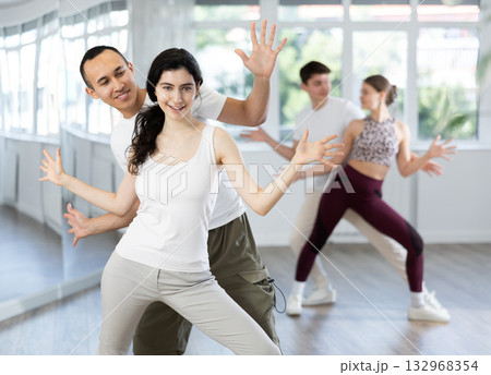Happy young woman and man enjoying active boogie-woogie dance in studio 132968354