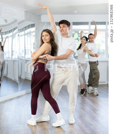Young girl with multinational group of active people training dancing couple active swing in studio 132968366