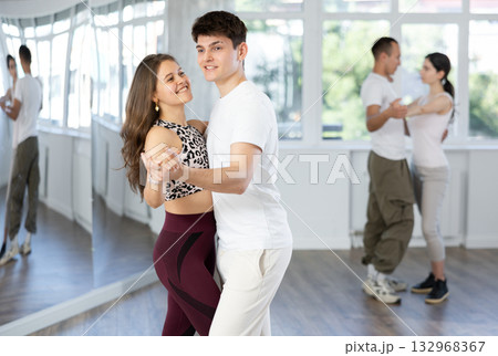 Young couple dancing playful bachata during group class 132968367