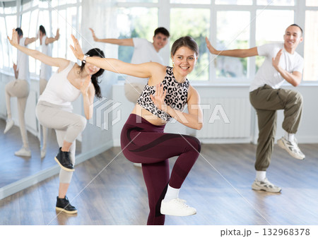 Smiling girl energizing group during dance fitness class Smiling girl energizing group during dance fitness class 132968378
