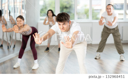 Group of women and men enjoying active dance movement in modern studio Group of women and men enjoying active dance movement in modern studio 132968451