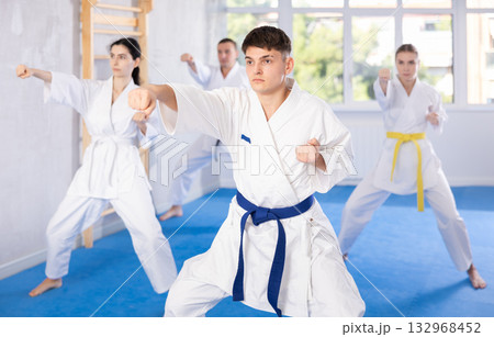 Middle-aged man attendee of karate classes practicing kata standing in row with others 132968452