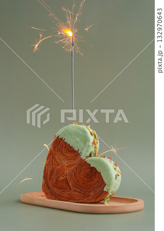 Festive holiday candle sparkler birthday anniversary celebration Heart shaped pistachio croissant on green background with copy space. Puff pastry trendy sweet dessert bakery. Creamy dough experiment Festive holiday candle sparkler birthday anniversary celebration Heart shaped pistachio croissant on green background with copy space. Puff pastry trendy sweet dessert bakery. Creamy dough experiment 132970643