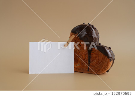 Mock up template paper note card Heart shaped dark chocolate croissant on beige background with copy space. Puff pastry new trendy sweet dessert bakery. Creamy dough 132970693