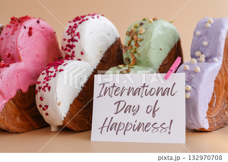 Holiday celebration INTERNATIONAL DAY OF HAPPINESS caption on greeting card Heart shaped different variety flavor croissants on beige background with copy space. Puff pastry new trendy sweet dessert 132970708