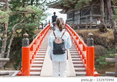 Woman tourist walking cross Sukashibashi bridge to the Zuiganji Godaido or National Treasure, a temple building on a small island in Matsushima Bay in Matsushima, Miyagi Prefecture, Tohoku, Japan 132970948