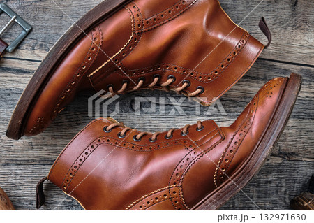 木製テーブルの上のウィングチップブーツと小物 132971630