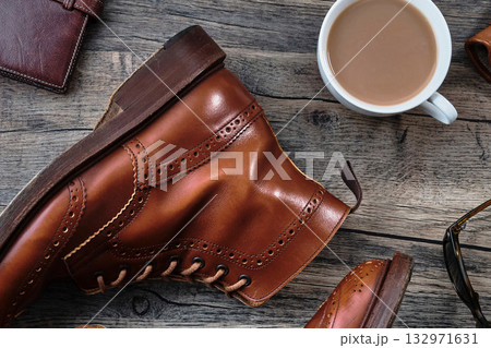 木製テーブルの上のウィングチップブーツと小物 132971631