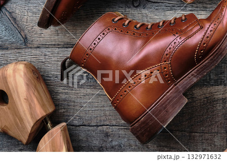 木製テーブルの上のウィングチップブーツと小物 132971632