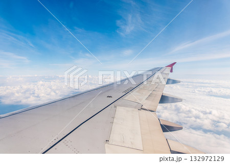 View from the airplane window at a beautiful cloudy sky and the airplane wing 132972129