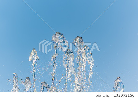 Splashes and jets of water against light background. Splashes and jets of water against light background. 132972156