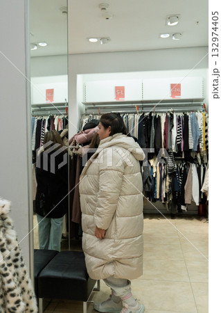 Woman Trying on Coat in Clothing Store 132974405