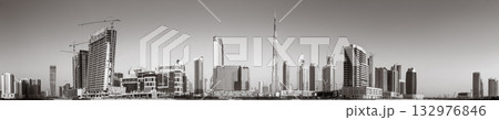 Monochrome city skyline with tall skyscrapers reflecting on calm water under a cloudy sky, Dubai Marina bay UAE Monochrome city skyline with tall skyscrapers reflecting on calm water under a cloudy sky, Dubai Marina bay UAE 132976846