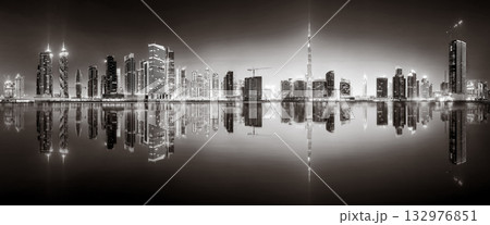 Urban city skyline with illuminated skyscrapers and waterfront railing in black and white at night, Dubai Marina bay UAE Urban city skyline with illuminated skyscrapers and waterfront railing in black and white at night, Dubai Marina bay UAE 132976851
