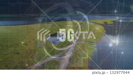 Radiating digital 5G graphic sending connectivity rings over riverside marshland, with dirt road 132977044