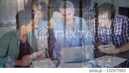 Three men using laptop tablet checking smartphone amid printed charts, glass reflection in office Three men using laptop tablet checking smartphone amid printed charts, glass reflection in office 132977063