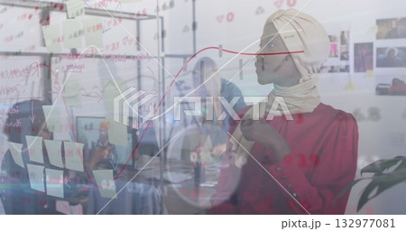 Working woman wearing beige headscarf red blouse adding sticky notes on board in office, copy space 132977081