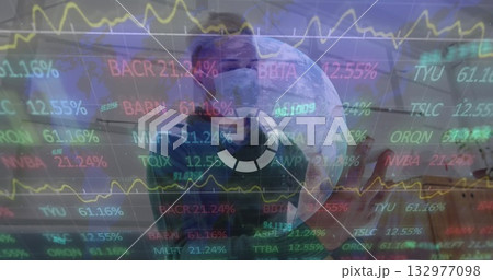Holding smartphone worker wearing scrubs cap mask in hospital corridor, stock ticker overlays Holding smartphone worker wearing scrubs cap mask in hospital corridor, stock ticker overlays 132977098