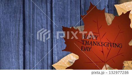 Featuring large brownish-red maple leaf bearing HAPPY THANKSGIVING DAY on blue planks, copy space 132977286