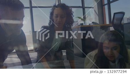 Leaning woman in gray blazer examining laptop on wooden table in office, with city skyline windows Leaning woman in gray blazer examining laptop on wooden table in office, with city skyline windows 132977294