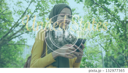 woman wearing green headscarf, yellow top holding smartphone and bag in park, United States overlay 132977365