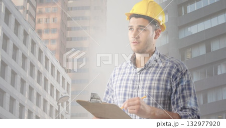 Inspecting engineer wearing hard hat taking notes on clipboard in downtown construction Inspecting engineer wearing hard hat taking notes on clipboard in downtown construction 132977920