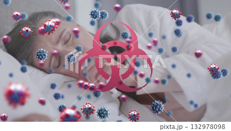 Resting woman lying in bed, holding tissue with virus particles and biohazard symbol 132978098