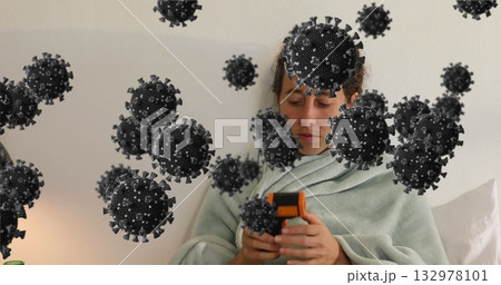 Woman wrapped in green blanket using thermometer to measure temperature in bedroom, virus overlay 132978101