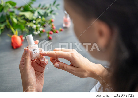 A woman points to a TPO-free label on a gel nail polish bottle. Awareness of safe cosmetics and the absence of Trimethylbenzoyl Diphenylphosphine Oxide. 132978725