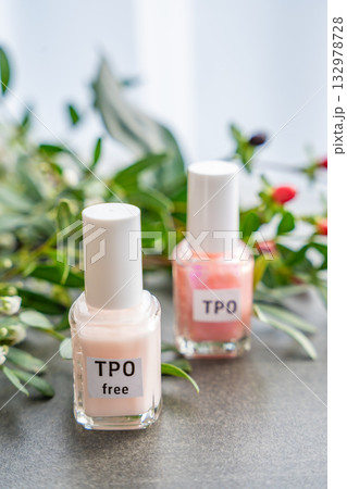 Two gel nail polish bottles labeled TPO and TPO Free on a table with flowers. Concept of chemical awareness and safe beauty products without Trimethylbenzoyl Diphenylphosphine Oxide 132978728