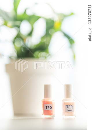 Two gel nail polish bottles labeled TPO and TPO Free on a table with flowers. Concept of chemical awareness and safe beauty products without Trimethylbenzoyl Diphenylphosphine Oxide 132978751