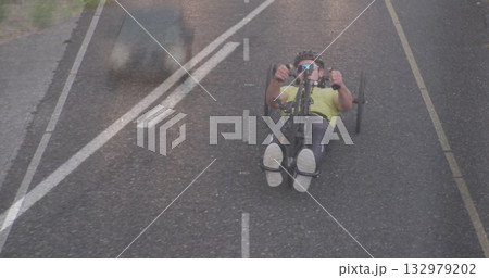 Riding recumbent cyclist wearing neon jersey helmet and sunglasses on rural road, with car shadow 132979202