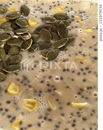 Close up of a bowl of delicious food of oatmeal with milk, pumpkin seeds and chia seeds, top view 132979550