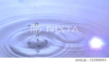 Hovering water droplet creating concentric ripples in studio water tank, with lens flare reflection Hovering water droplet creating concentric ripples in studio water tank, with lens flare reflection 132980043
