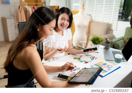 Female fashion designers discussing new clothing collection ideas in studio. 132980287