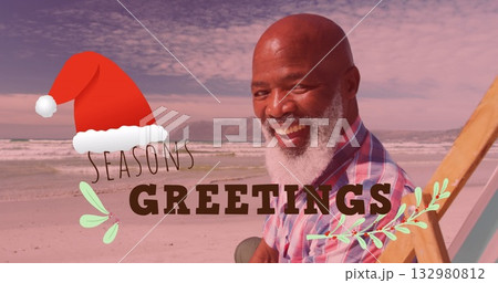 Sitting man wearing plaid shirt on sandy beach chair, with Seasons Greetings overlay, copy space Sitting man wearing plaid shirt on sandy beach chair, with Seasons Greetings overlay, copy space 132980812