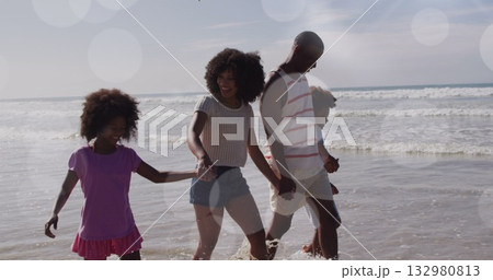 Walking family of four holding hands along sandy beach shoreline, with sunlight bokeh reflections Walking family of four holding hands along sandy beach shoreline, with sunlight bokeh reflections 132980813