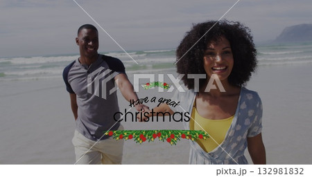 Walking couple holding hands along sandy shore under cloudy sky, with holiday greeting graphic Walking couple holding hands along sandy shore under cloudy sky, with holiday greeting graphic 132981832