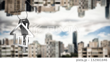 Hanging metal keyring carrying house-shaped pendant and keys in front of city skyline, copy space 132981846