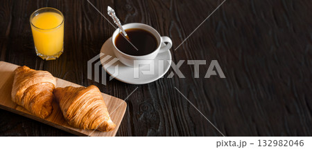 Two croissants on a wooden cutting board. Rustic dark table. Food banner. Tasty fresh croissant, jam, orange juice. Continental breakfast served with freshly baked pastry. Close up view, Good morning Two croissants on a wooden cutting board. Rustic dark table. Food banner. Tasty fresh croissant, jam, orange juice. Continental breakfast served with freshly baked pastry. Close up view, Good morning 132982046