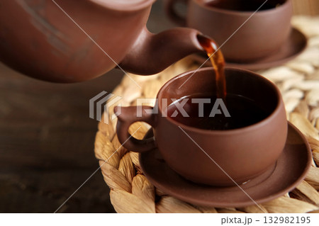 Tea Ceremony. Traditional Asian Tea Utensil, Serving Authentic Set. Person Pouring Tea from Brown Pottery Teapot to Teacup. Bamboo Tray. Lifestyle. Wellness Balance Health. Tea Brewing Equipment 132982195