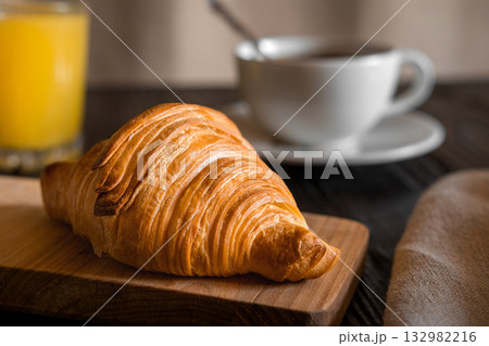 Coffee cup with croissant on a rustic dark wooden table. Food series. Two tasty fresh croissants, jam, orange juice. Continental breakfast served with freshly baked pastry. Close up view, Good morning 132982216