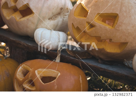 Halloween Pumpkin Head with Carved Scary Smiling Face on Wood Bench Outside. Jack-O-Lantern, Burning Candles, Dried Leaves Outdoors. Halloween Composition for Backyard Decor. Pumpkins. All Saints Day. Halloween Pumpkin Head with Carved Scary Smiling Face on Wood Bench Outside. Jack-O-Lantern, Burning Candles, Dried Leaves Outdoors. Halloween Composition for Backyard Decor. Pumpkins. All Saints Day. 132982371