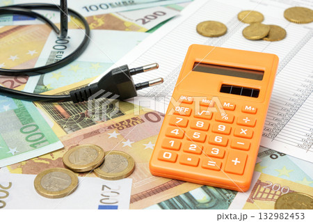Power plug and Calculator on Euro Banknotes Background. Increasing Consumption. Cost of Electricity, Expensive Energy Concept. Price Hike. Heating Crisis. Utility Bill Saving, Conservation. Inflation 132982453